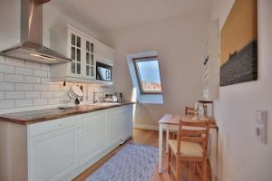 a kitchen with white cabinets and a wooden table at Haus zur Niendorfer Sonne Haus Schwalbennest in Niendorf +11 photos