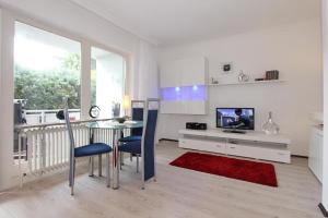 een witte woonkamer met een tafel en een tv bij Fh Dornkampstraße 1 Ferienhaus Dornkampstrasse 1 Appartement 2 in Timmendorfer Strand