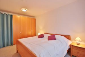 um quarto com uma cama branca e 2 almofadas vermelhas em Wohnpark am Mühlenteich Wohnpark am Mühlenteich Appartement 09 em Timmendorfer Strand