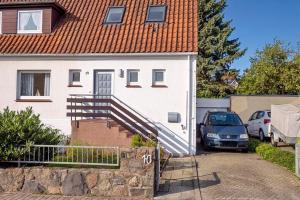 una casa blanca con una escalera junto a un coche en Haus Lubecca Ferienhaus Lubecca Appartement 01, en Timmendorfer Strand
