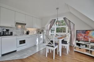 a kitchen with white cabinets and a table and a tv at Im Brook 36-38 Am Elchgrund Appartement 12 in Timmendorfer Strand