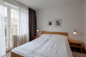 ein Schlafzimmer mit einem weißen Bett und einem großen Fenster in der Unterkunft Am Rosenhain 6 Am Rosenhain 6 Appartement 1 in Timmendorfer Strand