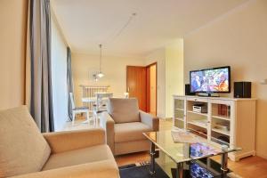 uma sala de estar com um sofá, uma televisão e uma mesa em Ferienanlage Bergstraße 62 Ferienhaus Bergstraße 62 Appartement 11 em Timmendorfer Strand