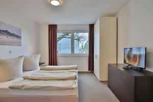 a hotel room with two beds and a flat screen tv at Villa Mér Baltique Villa Mér Baltique Appartement 13 in Timmendorfer Strand