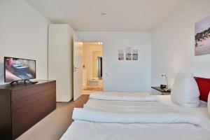 two beds in a white room with a television at Villa Mér Baltique Villa Mér Baltique Appartement 13 in Timmendorfer Strand