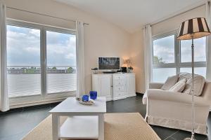 een woonkamer met een bank, een tv en ramen bij Penthouse am Platz Penthouse am Platz Appartement 10 in Timmendorfer Strand