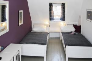 Duas camas num pequeno quarto com paredes roxas em Lütthus-Timmendorf Lütthus-Timmendorf em Timmendorfer Strand