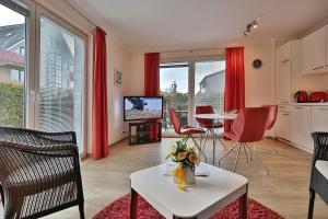 un soggiorno con tende rosse, tavolo e TV di Domizil am Meer Domizil am Meer Appartement 07 a Timmendorfer Strand