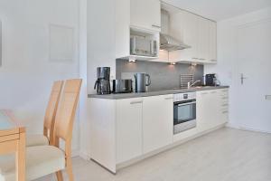 a kitchen with white cabinets and a table and a chair at Haus Miramar Treffert Appartement 38 in Niendorf