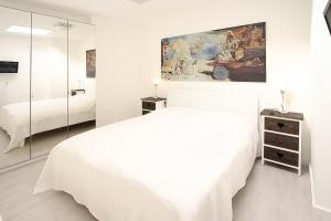 Un dormitorio blanco con una cama blanca y un espejo. en Haus Miramar Treffert Appartement 38, en Niendorf