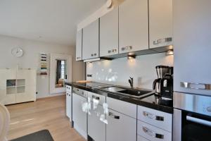 een keuken met witte kasten en een wastafel bij Am Rosenhain 12 Am Rosenhain 12 Appartement 1 in Timmendorfer Strand