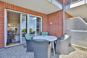 een patio met een tafel en stoelen en een bakstenen muur bij Haus Windrose Windrose Appartement 3 in Scharbeutz