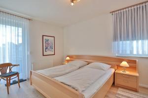 um quarto com uma cama, uma cadeira e uma janela em Barke Barke Appartement 307 em Scharbeutz