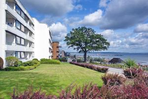 a building with a green lawn next to the ocean at Hanseat am Hang 3 - 5 Strandhafer Appartement 5 in Scharbeutz