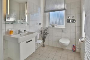 uma casa de banho branca com um lavatório e um WC em Barke Barke Appartement 307 em Scharbeutz