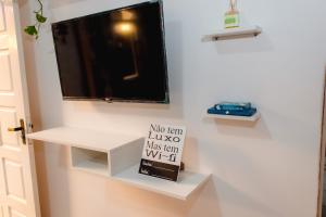 a flat screen tv on a wall with a shelf at Moni & Junior Hospedagem in Angra dos Reis