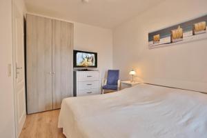 a bedroom with a white bed and a tv at Seepark Seepark Appartement 2 in Scharbeutz