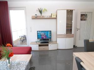 uma sala de estar com uma televisão e um sofá vermelho em Strandglück Haus B Strandglück Appartement 12B em Scharbeutz