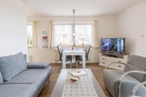 un soggiorno con divano, tavolo e TV di Ostseeblick Ostseeblick Appartement 13 a Scharbeutz