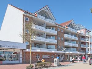 un immeuble d'appartements avec des personnes assises à l'extérieur dans l'établissement Residenz Ostseestrand Appartement 14, à Scharbeutz