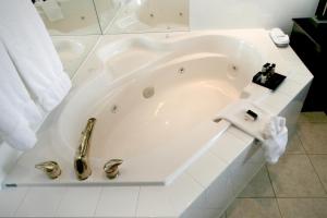 La salle de bains est pourvue d'une baignoire blanche avec un robinet. dans l'établissement Foxwood Inn & Suites Drayton Valley, à Drayton Valley