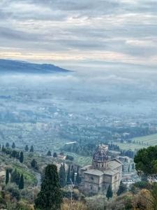 un antiguo edificio en la cima de una colina con un valle nublado en Appartamenti Belvedere, en Cortona