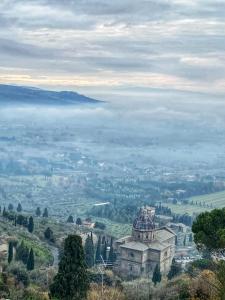 an old building on top of a hill with a foggy valley at Appartamenti Belvedere in Cortona