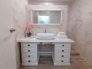 een witte badkamer met een wastafel en een spiegel bij Gelvesturist 2 in Gelves