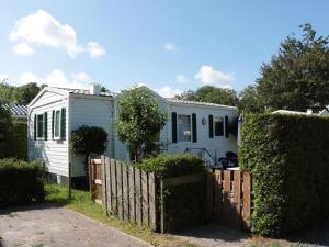 a small white house with a wooden fence at Captivating chalet with a microwave, near the Wadden Sea in Tzummarum