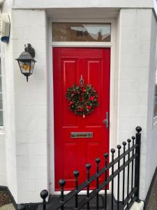 a red door with a wreath on it at Lovely Entire 1 Bedroom Flat with Patio in Chiswick in London