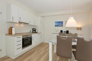 uma cozinha com armários brancos e uma mesa com cadeiras em Villa Stern Villa Stern Appartement 06 em Timmendorfer Strand