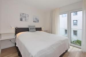 een witte slaapkamer met een groot bed en een raam bij Villa Stern Villa Stern Appartement 06 in Timmendorfer Strand