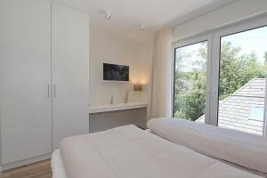 een witte slaapkamer met 2 bedden en een raam bij Villa Stern Villa Stern Appartement 09 in Timmendorfer Strand