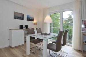 une salle à manger blanche avec une table et des chaises en verre dans l'établissement Villa Stern Villa Stern Appartement 08, à Timmendorfer Strand