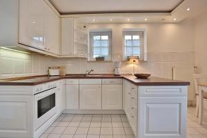 eine Küche mit weißen Schränken und einem Waschbecken in der Unterkunft Haus Parkblick, Timmendorfer Strand Haus Parkblick Appartement 07 in Timmendorfer Strand
