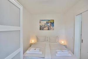 Schlafzimmer mit einem Bett mit weißer Bettwäsche und Handtüchern in der Unterkunft Haus am Höppnerweg 5 Haus am Höppnerweg 5 Appartement 09 in Timmendorfer Strand