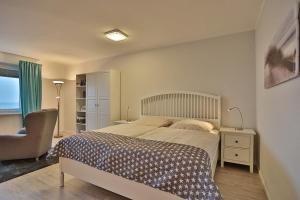 a bedroom with a large bed and a chair at Haus Seebrücke Haus Seebrücke Appartement 08 in Niendorf
