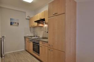 a kitchen with wooden cabinets and a stove top oven at Haus Seebrücke Haus Seebrücke Appartement 08 in Niendorf