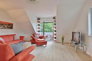 ein Wohnzimmer mit orangefarbenen Möbeln und einem TV in der Unterkunft Haus Bergstrasse 4 Haus Bergstraße 4 Appartement 9 in Timmendorfer Strand
