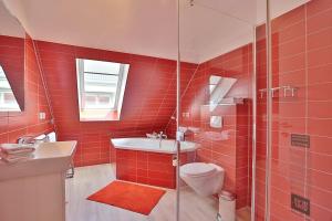ein rot gefliestes Bad mit einem WC und einer Dusche in der Unterkunft Haus Bergstrasse 4 Haus Bergstraße 4 Appartement 9 in Timmendorfer Strand + 13 Fotos