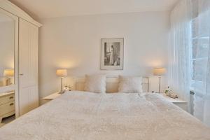 een witte slaapkamer met een groot bed met 2 lampen bij Am Elchgrund, im Brook 9 Am Elchgrund Im Brook 9 Appartement 02 in Timmendorfer Strand