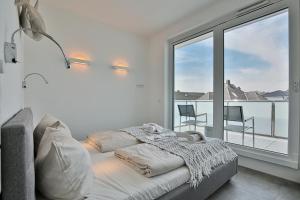 ein weißes Schlafzimmer mit einem Bett und einem großen Fenster in der Unterkunft Haus Wolburgstraße 1 Haus Wolburgstraße 1a Penthouse Haifisch Appartement 5 in Timmendorfer Strand