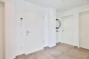 einen Flur mit weißen Wänden und einer Tür in der Unterkunft Haus Wolburgstraße 1 Haus Wolburgstraße 1a Penthouse Haifisch Appartement 5 in Timmendorfer Strand + 33 Fotos