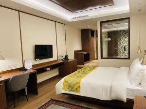 a bedroom with a bed and a desk and a television at Noblestride Resort in Gangtok