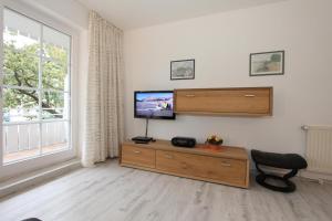 a living room with a tv and a chair and a window at Haus Parkblick Parkblick Appartement 4 in Scharbeutz