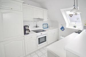 una cocina blanca con armarios blancos y fregadero en Maisonnette mit Charme Maisonette mit Charme, en Scharbeutz