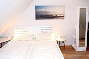 1 dormitorio con 1 cama blanca y 2 sillas en Maisonnette mit Charme Maisonette mit Charme, en Scharbeutz