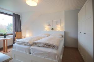 1 dormitorio con 1 cama con sábanas blancas y ventana en Appartemenhaus Linda-Lu Appartementhaus Linda-Lu Appartement 7, en Scharbeutz