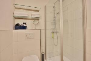 a white bathroom with a shower and a toilet at Haus Stranddistel Stranddistel Appartement 2 in Scharbeutz +16 photos