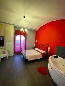 a bedroom with a red wall and a bed and a tub at Villa Gaia - Luxury Villa, pool & wellness rooms in Bordighera